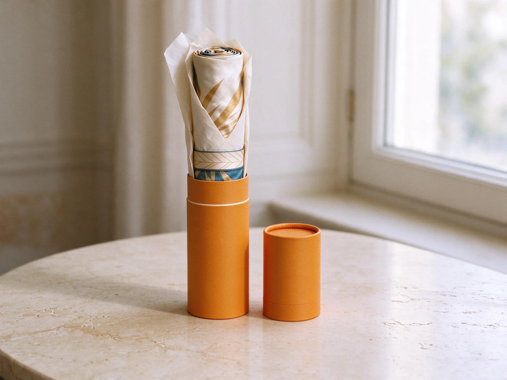 the slim orange tube with its cap off, the silk kimono rolled in tissue rising out of it